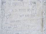 une plaque en pierre fixée sur le mur d'un immeuble et sur laquelle figurent des inscriptions