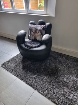 a black chair with a pillow on it in front of a window