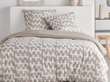 un lit blanc avec une couette beige et des oreillers dans une chambre