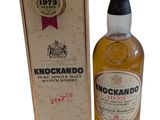 une photo d'une bouteille de whisky Knockandoo posée à côté d'une boîte