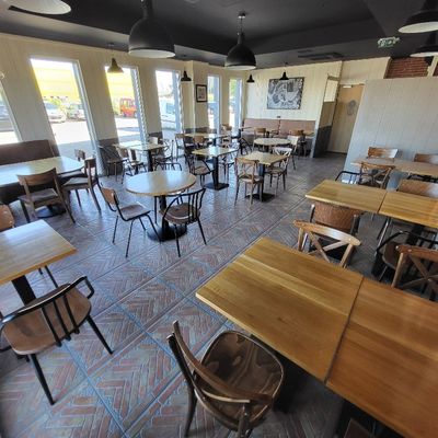 de nombreuses tables et chaises dans un restaurant doté de nombreuses fenêtres