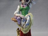 a figurine of a woman holding a basket of flowers