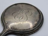 a silver mirror with a monogram on it on a table