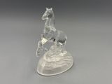 figurine en cristal représentant un cheval sur un rocher, sur fond gris
