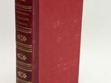 an old red book sitting on top of a white table