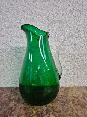 un pichet en verre vert posé sur une table en marbre