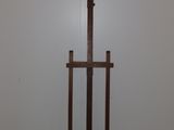 a wooden easel in the corner of a room with a white wall