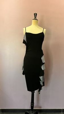 La robe est posée sur un mannequin devant un mur rose.