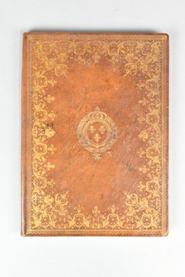 an old book with a gold cover on a white surface