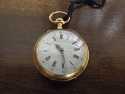une montre de poche en or, ornée de chiffres romains, posée sur une table
