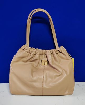 a tan purse with a yellow handle on a white table
