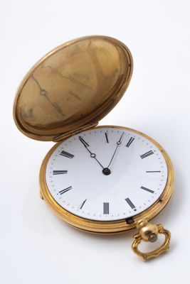 a gold pocket watch sitting on a white surface