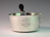 a silver pot with a black handle on a white table