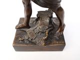bronze statue of a man kneeling on a box with a dog