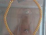 someone is taking a picture of a gold necklace in a glass case