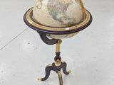 un vieux globe terrestre posé sur un trépied dans une pièce