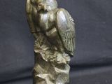 statue of a bird perched on a rock on a black background