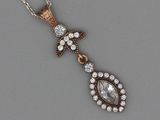 une photo représentant un pendentif en diamant suspendu à une chaîne, posé sur une surface grise