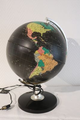 un globe noir orné d'une carte, posé sur un socle