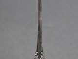 an antique silver spoon with a gold rim on a gray surface