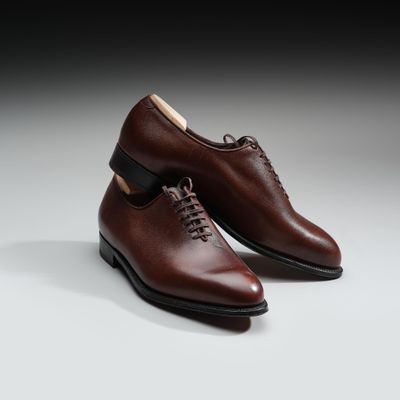 une paire de chaussures marron posée sur une surface blanche