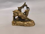 une statue en or représentant une chèvre et un oiseau posés sur un rocher