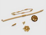 an assortment of gold jewelry including a chain, bracelet, and broochet