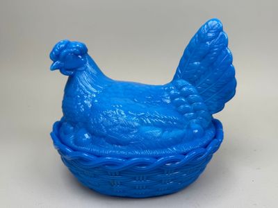 un poulet en plastique bleu posé dans un panier sur une table