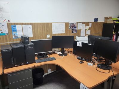 une photo d'un bureau avec trois écrans d'ordinateur et une imprimante
