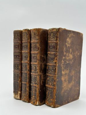 trois vieux livres posés l'un sur l'autre sur une surface blanche