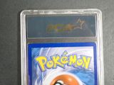 the pokemon card is in a plastic case on a table