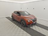 La voiture orange est garée dans le garage, sur le sol à damier.