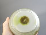 a person holding a glass jar with a green liquid inside of it