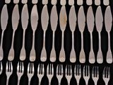 a lot of forks and spoons on a black table