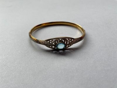 gros plan d'une bague en or avec une pierre bleue