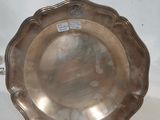 une assiette en argent antique avec une poignée sur une surface blanche