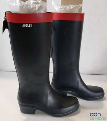 pair of black rain boots with red trims on a white surface