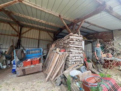 a man that is standing in front of a pile of wood
