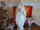 a statue of the virgin mary on a table next to wine glasses