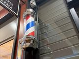 a barber pole in front of a building with a sign on it