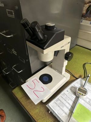 un microscope posé sur un bureau, à côté d'un classeur
