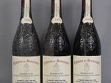 trois bouteilles de vin sont posées sur une étagère en verre devant un fond gris