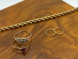 two gold rings and a gold chain on a wooden tray