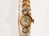 une montre-bracelet en or sertie de diamants, posée sur un fond blanc