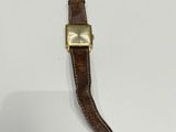 an image of a watch on a white surface with a brown strap