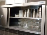 a stainless steel cabinet with dishes and cups in it