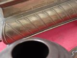 un vase en argent posé sur une table rose