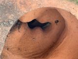 a brown vase with a hole in it sitting on the ground