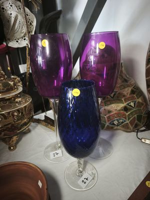 purple and blue wine glasses sitting on top of a white table