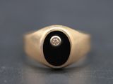 a gold ring with a black onyx stone and a diamond